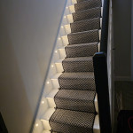 stairs with a carpet runner and spotlights